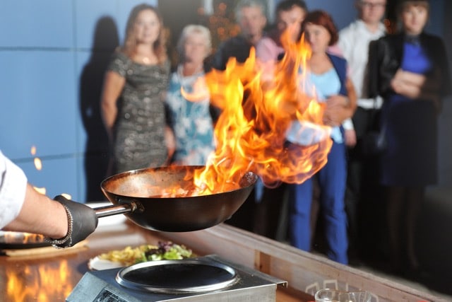 Das Bild zeigt ein Show Cooking mit Feuer, dass live am Wok zelebriert wird.