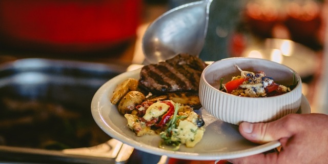 Das Foto zeigt, wie sich ein Gast am Grillbuffet bedient.